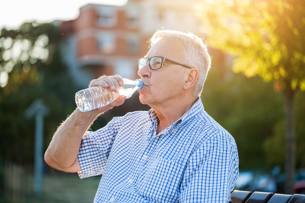 A senior man drinking from a bottle of water