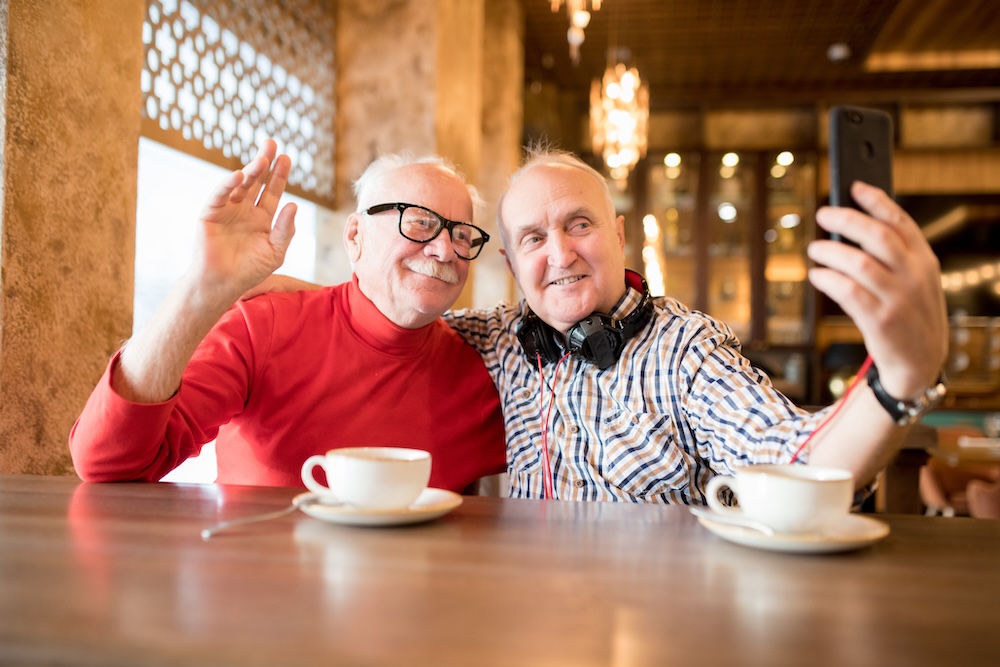 Two senior men having coffee and taking advantage of the ways technology makes senior living community yorba linda better