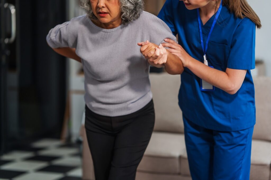 Physical therapist guiding an older adult through balance and strength exercises after a fall